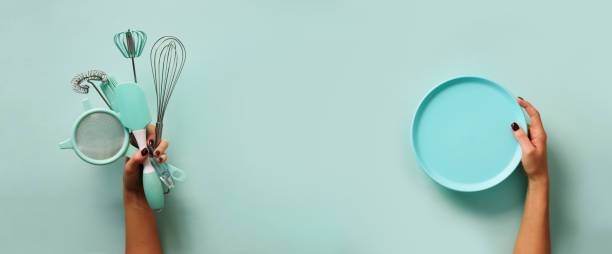 istock Baking flat lay. Female hands holding plate, kitchen tools, sieve, rolling pin, spatula and bruch on pastel blue background. Banner with copy space 1149547219