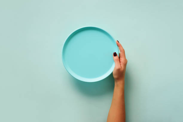 istock Female hand holding empty blue plate on pastel background with copy space. Healthy eating, dieting concept. Banner 1149547238