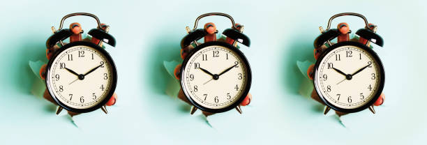 istock Seamless pattern of hands holding black alarm clock through hole in blue paper background. Wake up alert concept. Morning routine. Minimalist style design. 1149552974