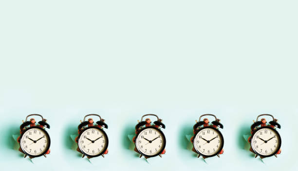 istock Pattern of hands holding black alarm clock through hole in blue paper background. Wake up alert concept. Morning routine. Minimalist style design. Banner with copy space 1149552987
