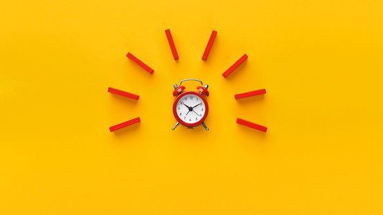 Reloj despertador con dominós rojos sobre fondo amarillo photo