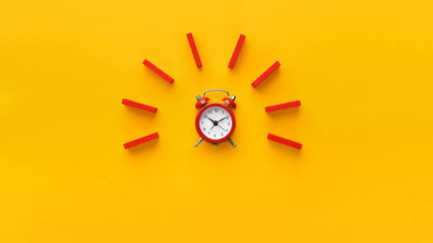 Alarm clock with red dominoes on yellow background Alarm clock with red wooden dominoes on yellow background. Minimalism concept, panorama with empty space time danger stock pictures, royalty-free photos & images