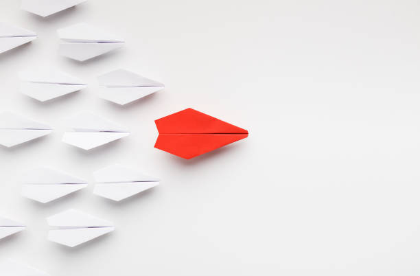 Red paper plane leading another ones, leadership concept Opinion leadership concept. Red paper plane leading another ones, influencing the crowd, white background, top view with free space persuasion photos stock pictures, royalty-free photos & images