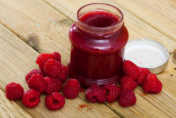 istock Image of tasty  raspberry jam in jar and fresh  berries on wooden surface 1149557237