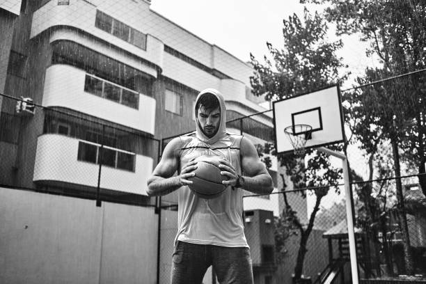 athletic young man playing basketball on a rainy day - basketball sport storm star imagens e fotografias de stock