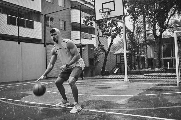 athletic young man playing basketball on a rainy day - basketball sport storm star imagens e fotografias de stock