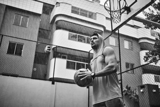 athletic young man playing basketball on a rainy day - basketball sport storm star imagens e fotografias de stock