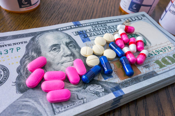 Medical expenses Medicine pills on a pile of 100 dollar bills and social security card social security social security card identity us currency stock pictures, royalty-free photos & images