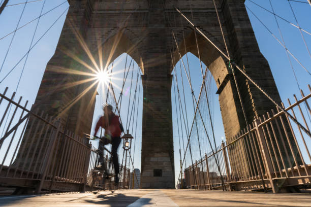 Scene of stop motion bicycle with Brooklyn bridge when sunrise, USA downtown skyline, Architecture and building with tourist concept stock photo