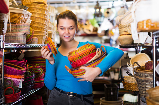 Female teen  choosing colour wicker basket in decoration and store