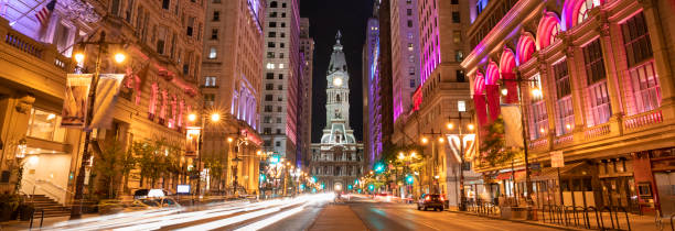Philadelphia City Hall and clock tower panorama on Broad Street at night Philadelphia city hall historic clock down Broad Street at night in Pennsylvania USA philadelphia pennsylvania photos stock pictures, royalty-free photos & images
