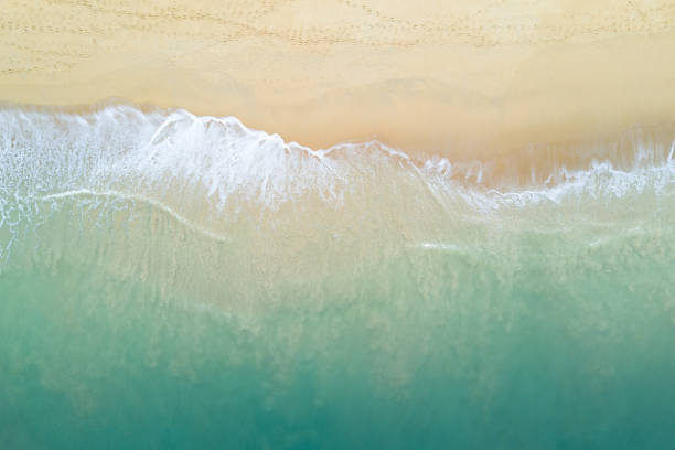 vista aerea dell'onda oceanica turchese che raggiunge la costa. bellissima spiaggia tropicale dalla vista dall'alto. mare delle andamane in thailandia. concetto di vacanza estiva - sand wave pattern beach wave foto e immagini stock