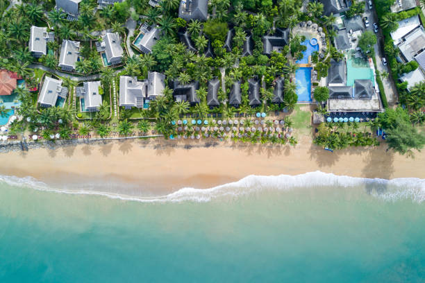 widok z lotu ptaka na ośrodek willi z drzewami kokosowymi, parasolami i leżakami na plaży. fala oceaniczna dociera do wybrzeża. piękna tropikalna plaża z góry. morze andamanów w tajlandii. koncepcja wakacji letnich - beach house zdjęcia i obrazy z banku zdjęć