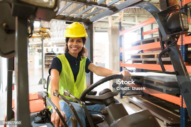 Smiling Female Worker Sitting On Forklift Stock Photo - Download Image Now - Forklift, Driving, Driver - Occupation