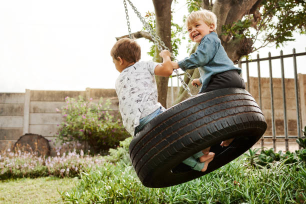 Shot of two adorable little boys playing on a swing together outdoors