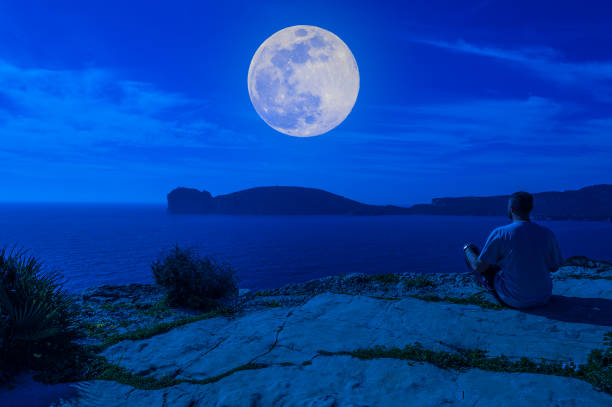 istock Man on the coast staring at the moon 1149578889