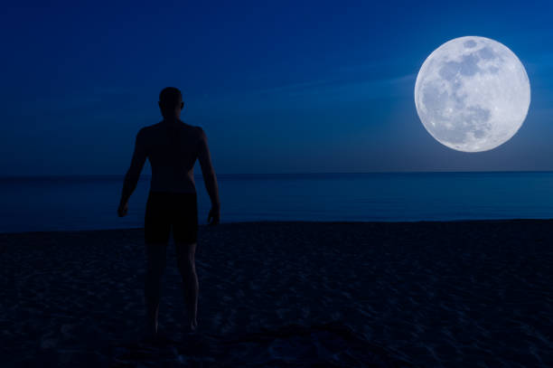 istock Shirtless man on the beach at night 1149579034