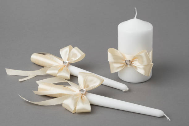 istock Three candles decorated with beige silk bows on gray background. 1149580476