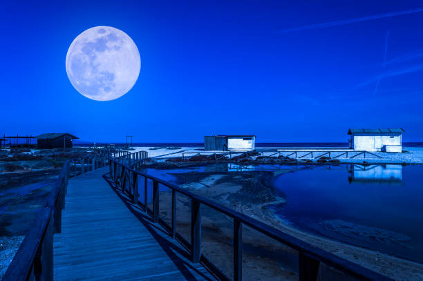 White cottage on the beach at night under the super moon