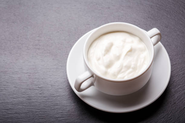 istock Greek yoghurt in white bowl on black slate background with copy space 1149586564