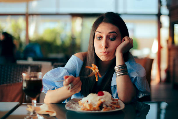 donna che si sente male mentre mangia un pasto enorme - eccesso foto e immagini stock