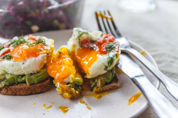 istock Breakfast served of two toasts with avocado, fried eggs with vegetables and herbs on a rustic tablecloth background. View from above. Healthy and nutritious food concept. 1149589760