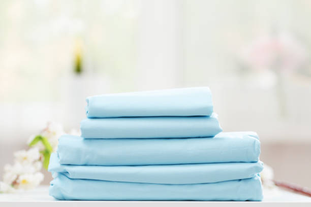 On the table is a stack of blue bedding on a blurred background.
