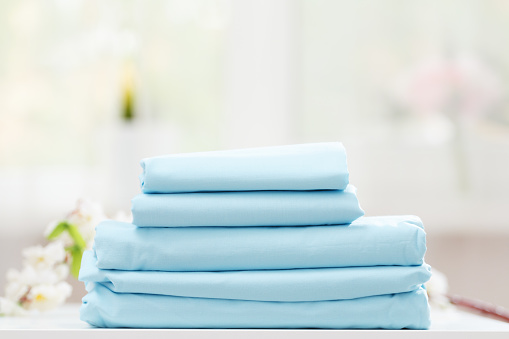 On the table is a stack of blue bedding on a blurred background.