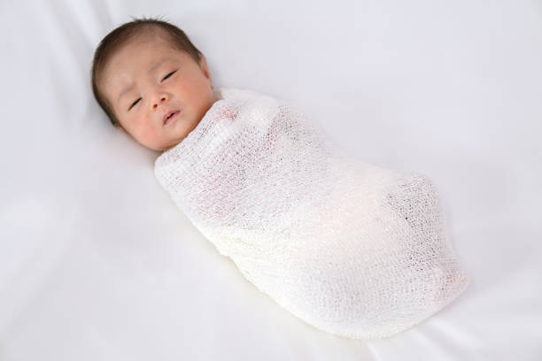 istock Adorable newborn baby in white wrap on white blanket background. 1149596880