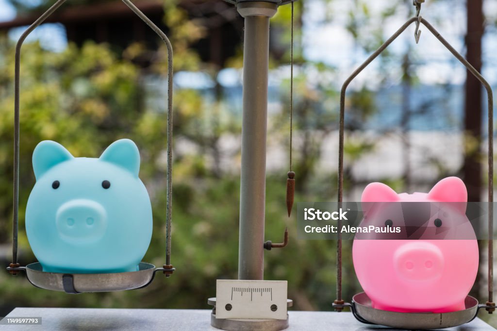 Male and Female Piggy Bank on Balance Concepts Stock Photo