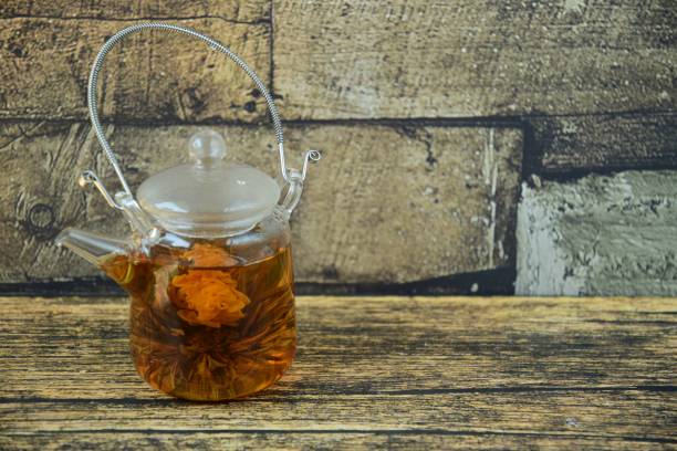 istock Teapot with a tea flower in it. Wooden background 1149598080