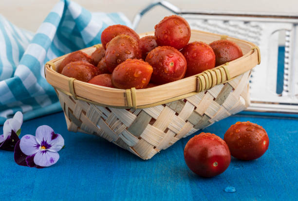 istock Cherry tomatoes (mini kumakos) with water drops. In wicker basket. 1149601219