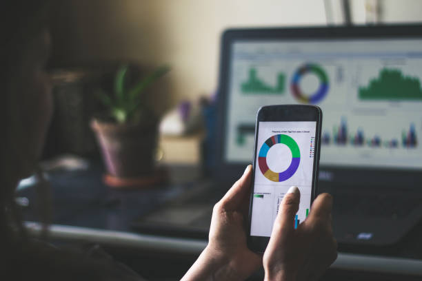 istock Female hands looking at the chart on phone with a laptop in background 1149601576