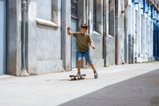 Front view of a cheerful skater boy riding on the street in a sunny day