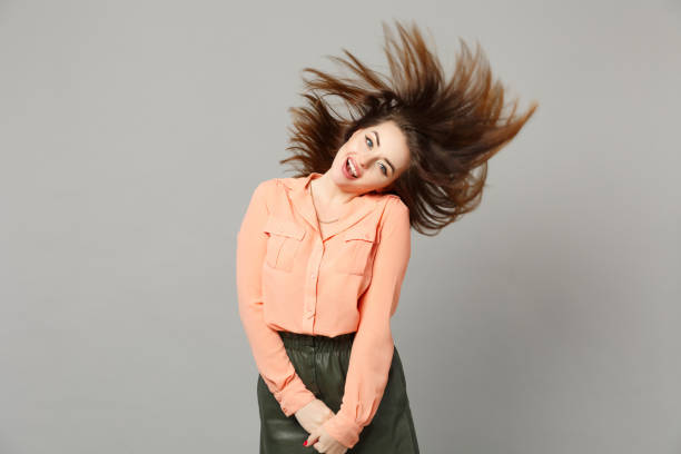 Portrait of cheerful funny young woman in pastel casual clothes with flowing hair having fun isolated on gray wall background in studio. People sincere emotions, lifestyle concept. Mock up copy space retrato de alegre jovencita divertida en ropa casual de color pastel con el cabello que fluye divirtiéndose aislado en el fondo de la pared gris en el estudio. personas emociones sinceras, concepto de estilo de vida. mock up espacio de copia.
