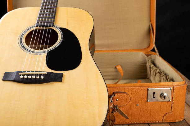 istock Classical guitar and suitcase on a dark wooden table. Stringed musical instrument on the go. Black background. 1149611633