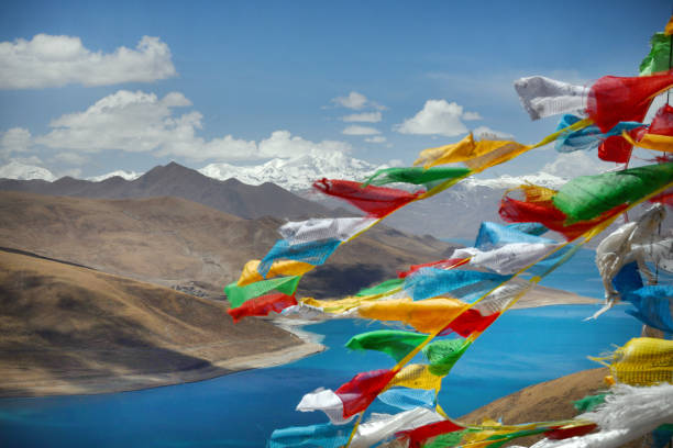 Prayer flags over Yamdrok Lake is a freshwater lake in Tibet, it is one of the three largest sacred lakes in Tibet. It is over 72 km long. The lake is surrounded by many snow-capped mountains and is fed by numerous small streams. The lake has an outlet stream at its far western end and means turquoise in English due to its color