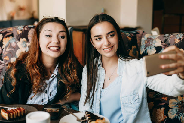 istock Two amazing girlfriends having fun in a coffee shop taking a selfie on the smartphone while drinking coffee and eating a cake. 1149618315