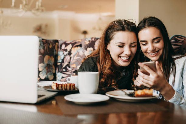 istock Two young beautiful caucasian woman having fun laughing while looking at a smartphone sitting in a coffee shop. 1149618363