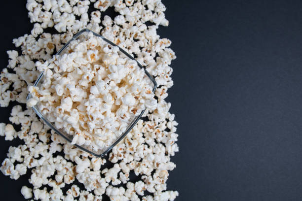 istock Popcorn in a glass bowl on a black background. Top view with copy space. 1149621216