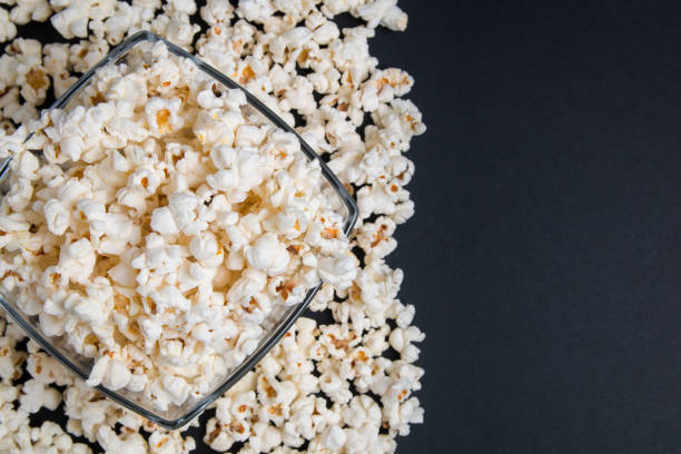 istock Popcorn in a glass bowl on a black background. Top view with copy space. 1149621231
