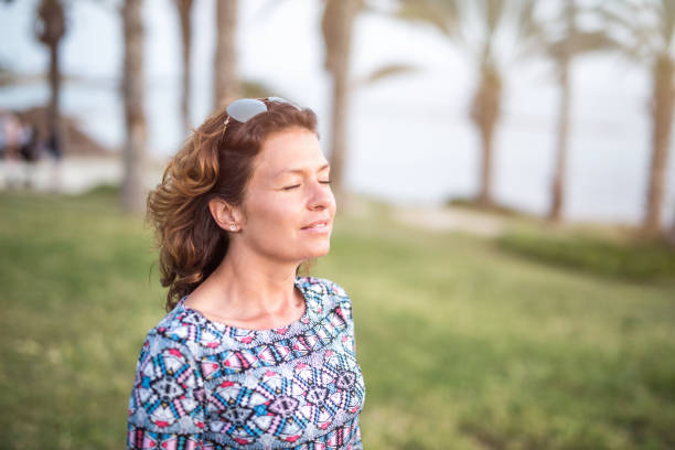 Happy mature woman day dreaming with eyes closed while on a vacation.