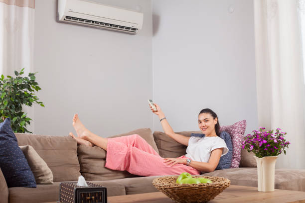 istock woman using remote control of air conditioner 1149637373