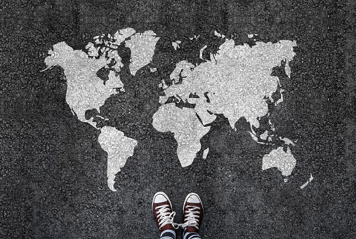 World map on an asphalt road an man in shoes