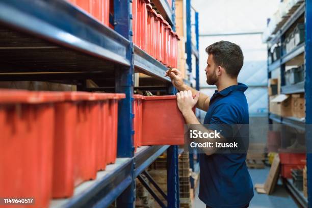 Warehouse Male Worker Examining Goods In Factory Stock Photo - Download Image Now - Warehouse Worker, Occupation, Warehouse