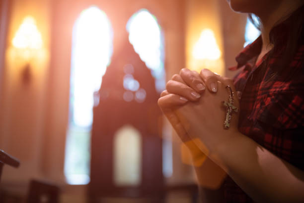 mujer mano sosteniendo rosario contra cruz y orando a dios en la iglesia. - rosario fotografías e imágenes de stock