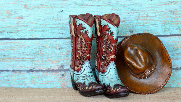 Cowboy boots and hat standing on a blue painted wood background
