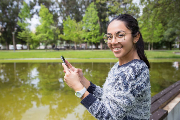 istock Happy young woman using smartphone in park 1149691563