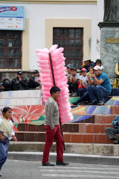 A portrait of 60-69 years old Turkish man. He is selling pink color cotton candy in the street. He is holding the cotton candies toward the blue sky.