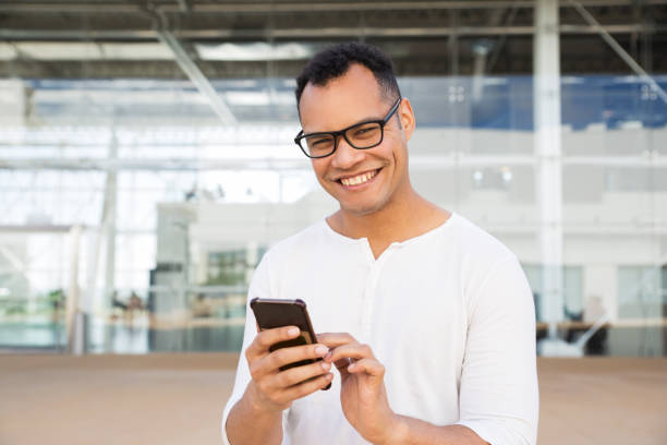 istock Smiling man standing at office building, holding phone in hands 1149692580